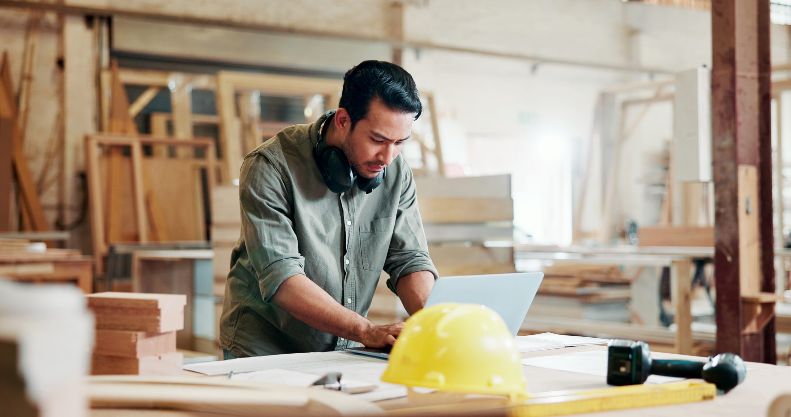 Construction contractor reviewing documents on a laptop at a job site workbench representing email security risks for construction companies