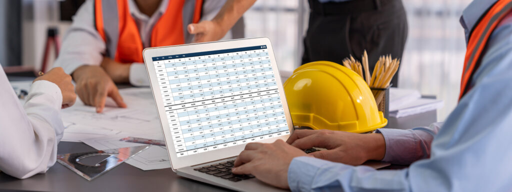 Construction workers reviewing invoice spreadsheet on a laptop representing billing and payment fraud risks for construction companies