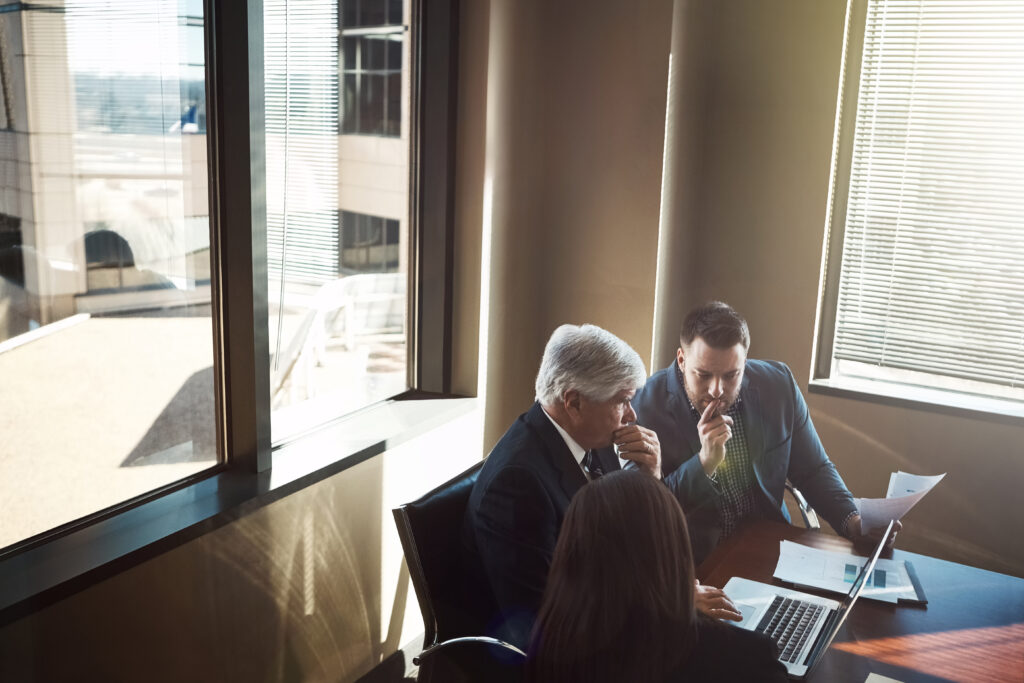 Two attorneys reviewing documents and laptops at a conference table representing law firm cybersecurity protocol review